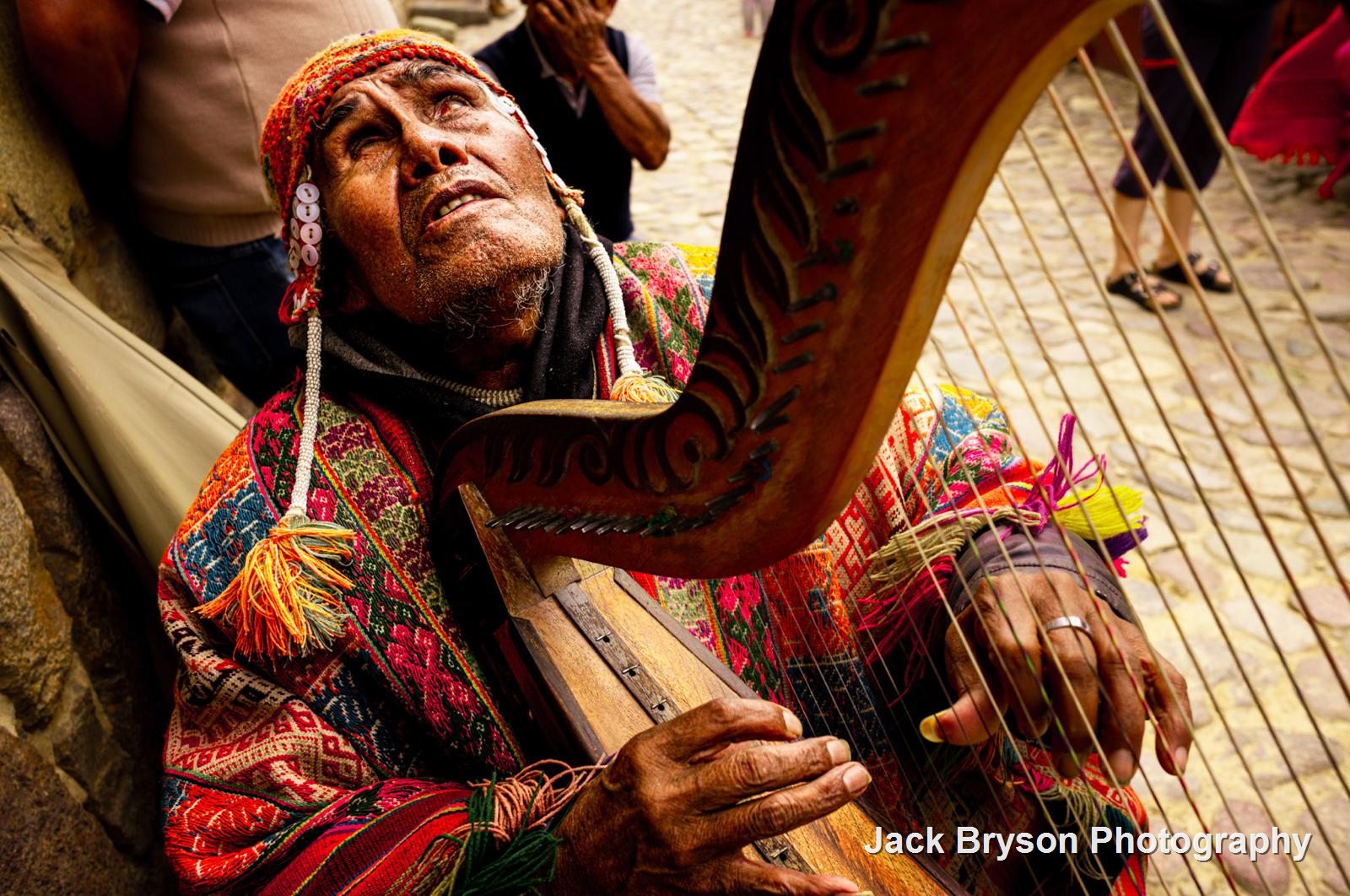 Colour street portrait of a blind musician playing a harp in Peru