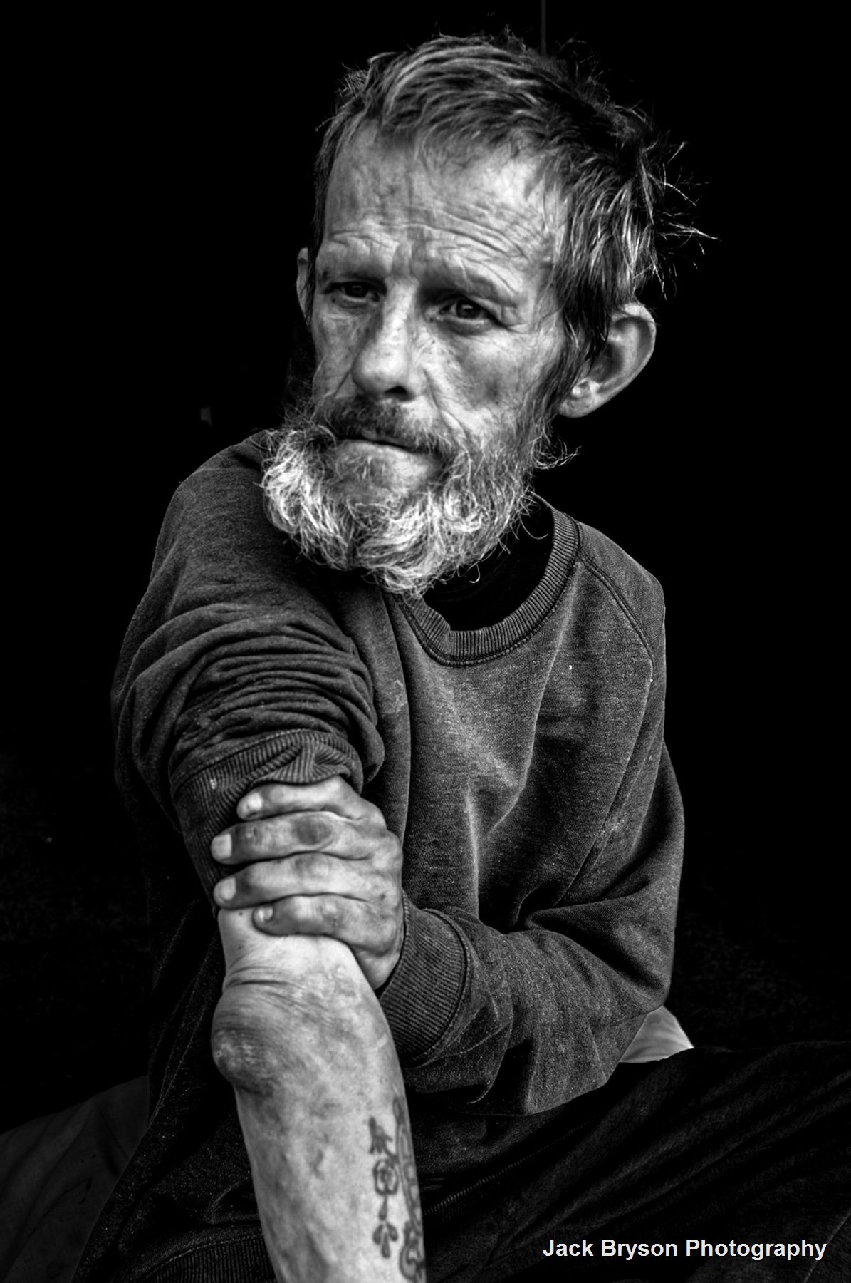 Black and white documentary portrait of Nigel seated in dramatic light