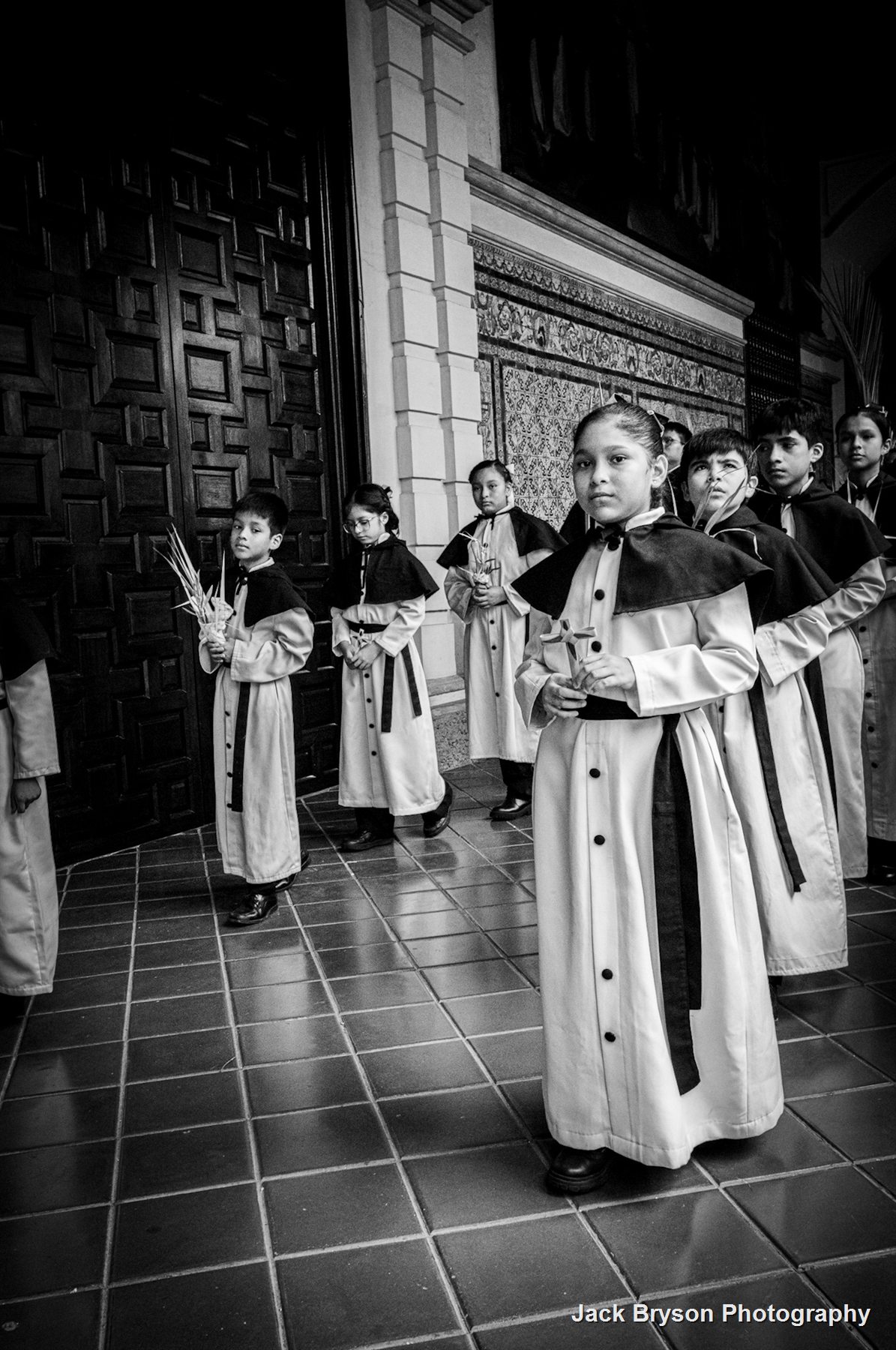 Black and white documentary photograph of children in a formal procession