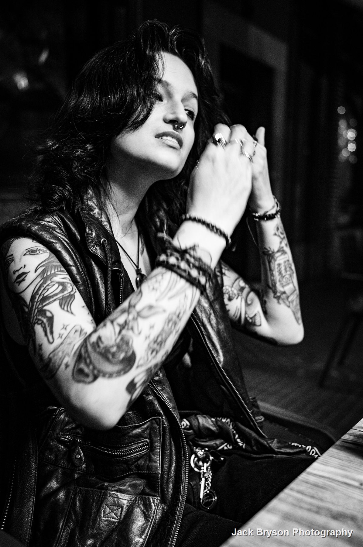 Black and white portrait of a tattooed person in a leather jacket